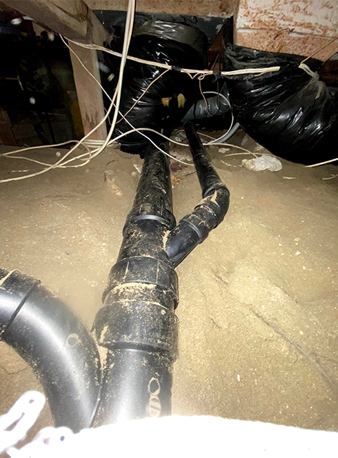 Plumber crouching to tighten piping beneath a residential bathroom sink