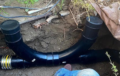 Plumber tightening a leaking pipe connection under a residential kitchen sink