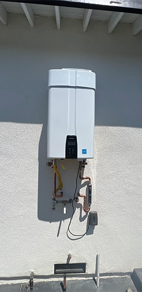 Homeowner talking with a plumber beside exposed pipes in a utility room